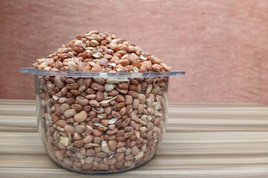 Şeffaf bir kâse içinde kahverengi organik fasulye yığını. Yapısını, şeklini ve büyüklüğünü gösteriyor.