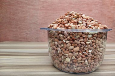 Şeffaf bir kâse içinde kahverengi organik fasulye yığını. Yapısını, şeklini ve büyüklüğünü gösteriyor.