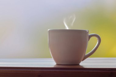 Gri yeşil arka planı ve kalp şeklinde buharı olan bir fincan çay ya da kahve.