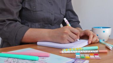 Girl student  in grey clothes writing in copybook, education or creativity concept