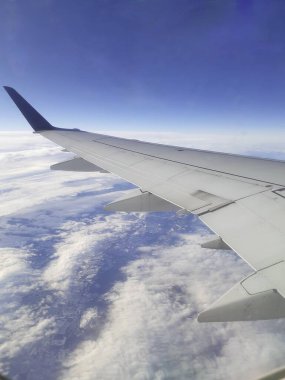 Resim, uçuş sırasında yüksek irtifada uçağın penceresinden manzarayı gösteriyor. Çerçevenin sağ tarafına karakteristik kanatları ve sonunda koyu bir kanadı olan uçağın kanadı hakimdir..