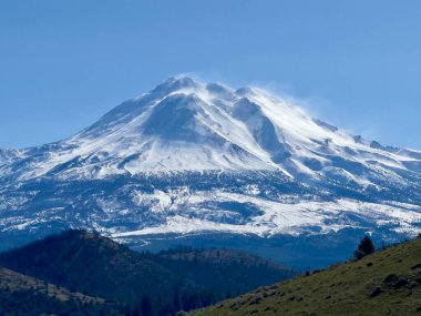 Bu görüntü görkemli bir dağ sırası olan panoramik bir manzara. Ön planda yol kenarının bir kısmını ve kuru, altın renkli otların olduğu bir alanı görebilirsiniz. Ortasında ender bulunan bir bitki örtüsüyle açık bir düzlük var. Dağlar muhteşem görünüyor. !!!