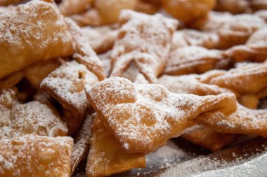 Yüksek çözünürlüklü melek kanatlı hamur işleri kalın pudralı şeker kaplama, detaylı çıtır çıtır kenarlı ve karlı dokular, Tusty Czwartek için geleneksel Polonya faworki, yüksek çözünürlüklü yemek dokusu fotoğrafçılığı, karnaval tatlı ayrıntıları..