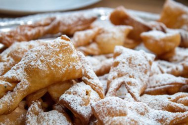 Kıtır melek kanatları (faworki) hamur işleri kalın katmanlı krema şekeri, gümüş tabakta detaylı doku, geleneksel Polonya usulü Tusty Czwartek tatlı ziyafeti, karlı şekerli ev yapımı hamur tatlısı, yiyecek fotoğrafçılığı.