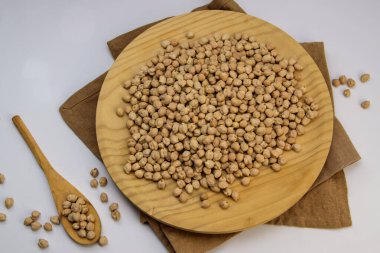 Tahta tabakta, kaşık ve çuval bezi ile kurumuş nohut yatağı. En az kırsal mutfak sahnesi.