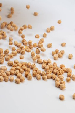 Pişmemiş kuru bezelyeler hareket halindeyken yakalanıp beyaz bir zemine saçıldılar. Dinamik gıda eylem konsepti.