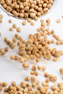 Pişmemiş kuru bezelyeler bir kaseden beyaz bir yüzeye dökülüyor hareket bulanıklığı ve dağınık taneler. Dinamik mutfak hareketi.