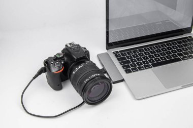 Bağlı çekim ayarları: DSLR kamera beyaz arka plandaki kabloyla dizüstü bilgisayara bağlandı. Fotoğraf aktarımı, yedekleme, post-prodüksiyon ve iş akışı kavramı.