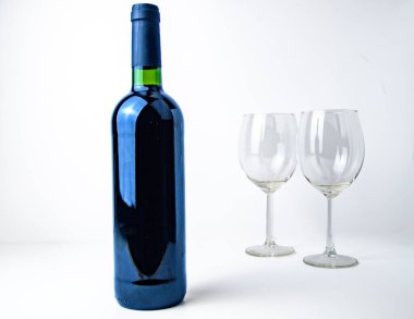 Solda jenerik bir şarap şişesi ve sağda iki boş bardak, beyaz üzerine izole edilmiş, geniş negatif alan..