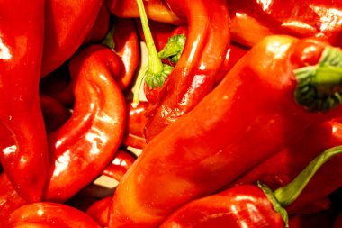 Kırmızı biber biberleri üst üste yığılmış, baharatlı yemek dokusu arka planda canlı kırmızı renkte..