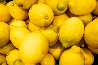 Taze limonlar üst üste yığılmış, parlak sarı arka planda turunçgil desenli..