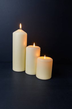 Karanlık arkaplanda mum ışığı üçlüsü, büyük kopya alanı, sıcak sıcak sıcak atmosfer.