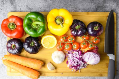 Üst manzara taze sebzeler, limon, sarımsak ve doğranmış soğan, bambu kesme tahtasının üzerinde bıçakla. Sağlıklı yemek ve bahar tarifi hazırlığı.