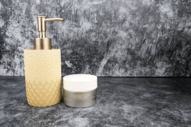 Altın pompalı bej sabun makinesi ve koyu desenli arka planda kozmetik krem kavanozu. Kopya alanı ile spa kişisel bakım kavramı.