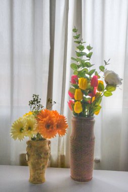 İki vazo lale, okaliptüs ve Gerbera çiçekleri, katıksız perdeler, yumuşak arka plan aydınlatma iç hayat sakin ruh hali ve kopyalama alanı ile.