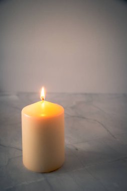 Yumuşak spot ışıkları ve boş arkaplanı olan tek bir yanan mum, asgari dua ve anma konsepti, Kutsal Hafta fotokopi alanı.