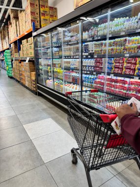 Rawang, Selangor, Malezya - 26 Ocak 2026: Bir depo süpermarketinde süt ve içecek ürünleriyle dolu soğutulmuş koridor boyunca market alışverişi yapan kişi.