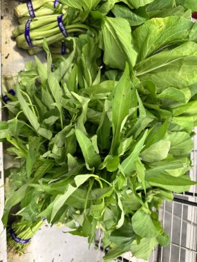 Taze Asya yapraklı sebzeler bir ürün pazarında tomar tomar olarak sergileniyor..