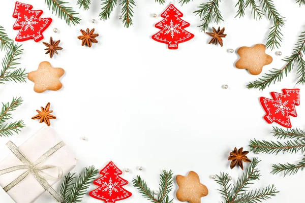 Christmas frame made of fir, red Christmas decorations, star anise and gingerbread cookies on a white background. Copy space. New Year's attributes. Flat lay.