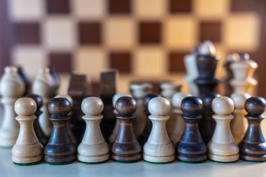 Tahtaya dizilmiş tahta satranç taşları var. Sahne konsantrasyon ve odaklanmadan oluşur. Parçalar kesin bir şekilde dizilir ve satranç oynamaya hazırdır.