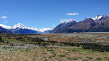 Arka planda açık mavi gökyüzü olan bir dağ sırası. Dağlar karla kaplı.