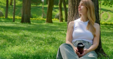 Parkta dinlenirken kahve içen bir kadın. Yüksek kalite fotoğraf