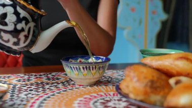 Özbek 'in iç kesiminde Samsa yakınlarında geleneksel yeşil çay kaseye dökülüyor. Yüksek kalite 4k görüntü