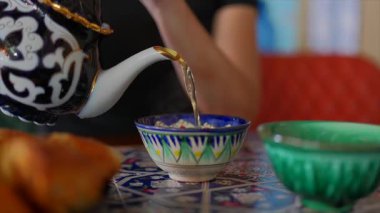 Özbek çay ortamında çaydanlıktan kaseye yeşil çay dökülüyor. Yüksek kalite 4k görüntü