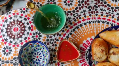 Özbek kafe ortamında samsa yakınlarında bir kaseye yeşil çay dökülüyor. Yüksek kalite 4k görüntü