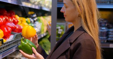 Kadın manavın sebze reyonundan dolmalık biber seçiyor. Yüksek kalite fotoğraf