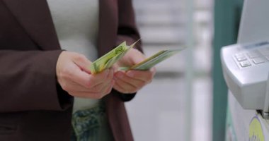 Kadın ATM ya da ödeme terminalinin yanında dururken Amerikan dolarlarını sayıyor. Yüksek kalite 4k görüntü