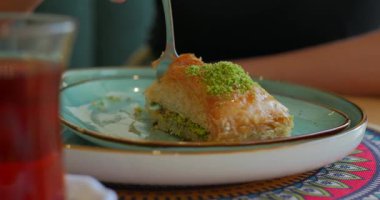 Çayla servis edilen şam fıstığı baklavasına çatal kesimi. Yüksek kalite 4k görüntü