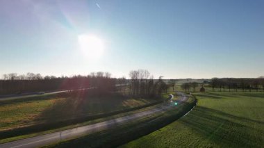 Güneşli kır yolu Alçak güneş ve uzun gölgeli çayırlarda kıvrılıyor, Sabah Bisikletçi Eğitimi
