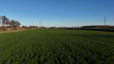 Açık Gökyüzü Altında Geniş Yeşil Alan, Geniş Çimenlik Halı ve Uzak Güç Sütunları ile Kaplanmış Geniş Çayırlar, Parlak