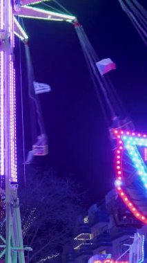 Bir lunaparkta dönen bir salıncakta parlayan neon ışıkları karanlık gece gökyüzüne karşı