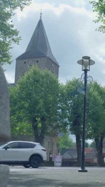 Günlük hayat, arka planda tarihi bir kilise bulunan klasik bir Avrupa köy meydanında sergileniyor.