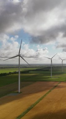 Rüzgar türbinleri yeşil ve altın tarlalar üzerinde dönüyor, temiz ve sürdürülebilir elektrik üretiyor