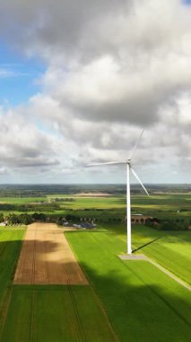 Yeşil tarım arazileri üzerinde temiz ve yenilenebilir enerji üreten büyük bir rüzgar türbininin havadan görünüşü