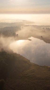 Havadan çekilen görüntülerde sakin bir göl yoğun bir sabah sisinin içinden altın gün doğumunu yansıtıyor.