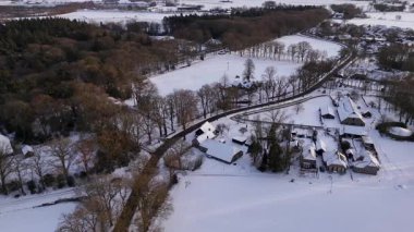 Köy şeridi karla kaplı köyde sallanıyor. Çatı katları, ağaçlar, insansız hava aracı yörüngeleri...