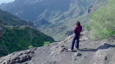 Uçuruma bakan ve vadiyi süpüren kişi sırt çantalı tek başına gezen gözcü.,