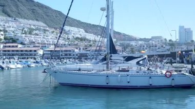 Sunlit Limanı 'nda demirli yelkenli. Tepe köyü, berrak mavi su, sakin esinti ve yumuşak hava.