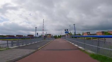 Pov çekimi modern bir Hollanda yerleşim bölgesinde kırmızı asfalt bisiklet yolu boyunca ilerliyor.