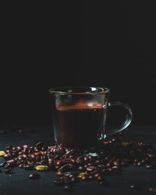 Karamsar kahve fotoğraflarında espresso, latte sanatı ve kahve çekirdekleri ve dramatik ışıklandırmayla birlikte cam bardaklarda taze demlenmiş kahve var..