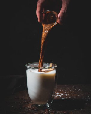 Karamsar kahve fotoğraflarında espresso, latte sanatı ve kahve çekirdekleri ve dramatik ışıklandırmayla birlikte cam bardaklarda taze demlenmiş kahve var..