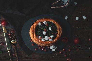 Lezzetli bir restoran menüsünde çeşitli hamur işleri vol-au-vent aperatifleri, kremalı tavuk, sığır eti ve ıspanaklı feta karışımı, koyu seramik tabaklarda kaplanmış ve gıda fotoğrafçılığı için taze garnitürlerle süslenmiş.