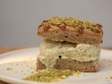 Beyaz bir tabakta ezilmiş şam fıstıklı tatlı dilimleri ahşap bir masada tatlı fotoğrafçılığı, ön manzara..