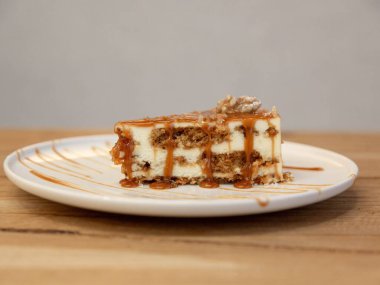 Beyaz tabakta karamel soslu karamel katmanlı tatlı dilimi, ahşap masada tatlı fotoğrafçılığı, ön manzara..