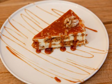 Beyaz tabakta karamel soslu karamel katmanlı tatlı dilimi, ahşap masada tatlı fotoğrafçılığı, ön manzara..