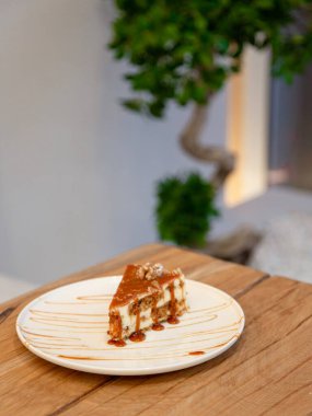 Beyaz tabakta karamel soslu karamel katmanlı tatlı dilimi, ahşap masada tatlı fotoğrafçılığı, ön manzara..